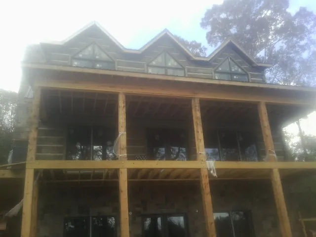 Dormers and porch framing on a large log home under construction — Roof Coating work by our crew in Newfield