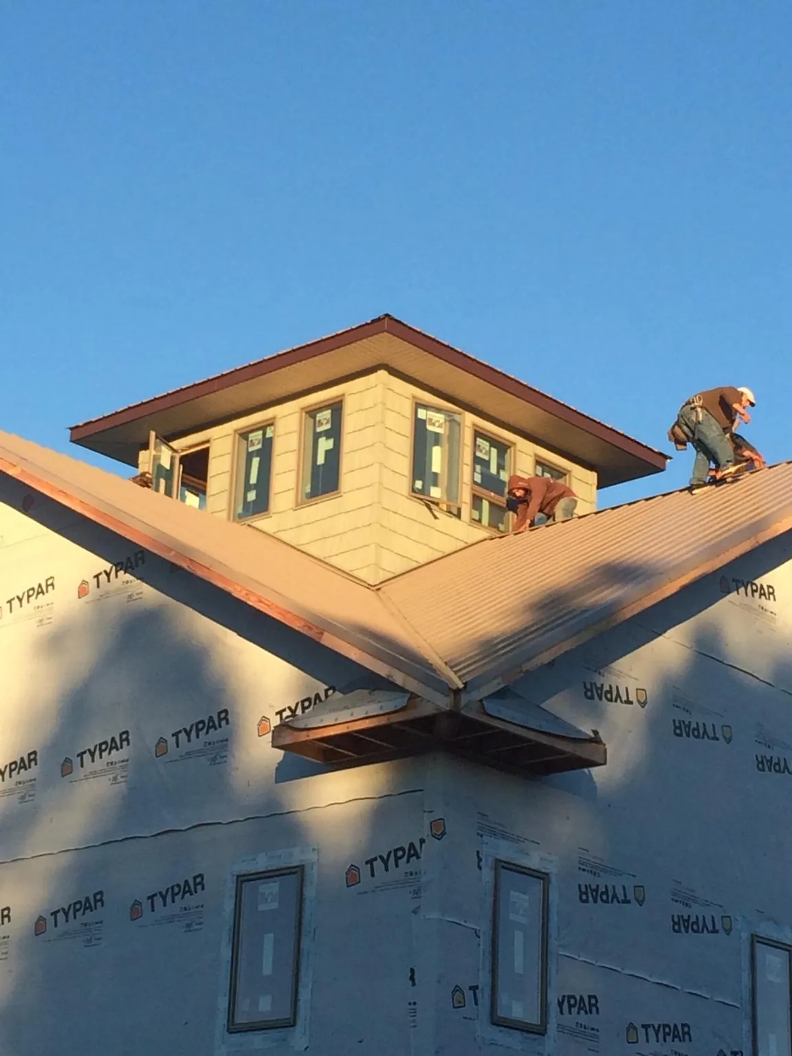Roofers working around a rooftop cupola on a new metal roof at sunset — Roof Waterproofing in Newfield by Roofing Brothers